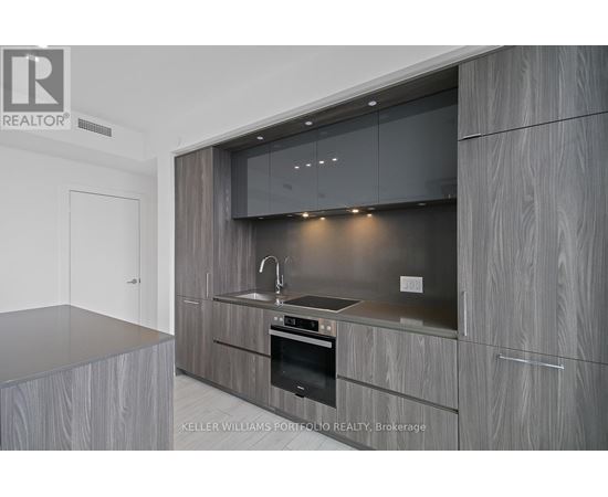 A modern kitchen with a stainless steel oven and wooden cabinets.