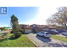 A realtor photo of a residential area with houses and cars.
