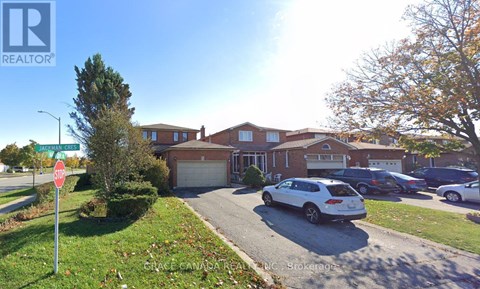 A realtor photo of a residential area with houses and cars.
