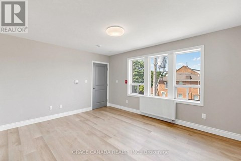 A room with a door and a window with a view of a building outside.