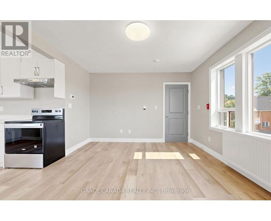A kitchen with a stainless steel oven and wooden flooring.