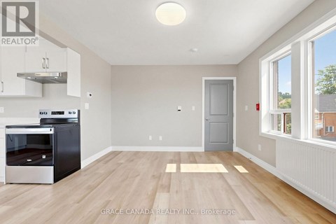 A kitchen with a stainless steel oven and wooden flooring.