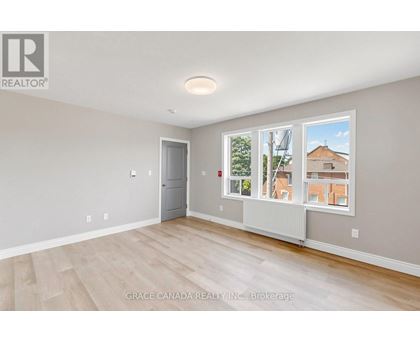A room with a door and a window with a view of a building outside.