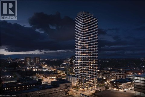 A tall, illuminated building stands in the center of a cityscape at night.