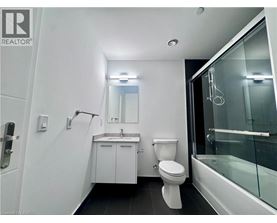 A white bathroom with a toilet, sink, and shower.