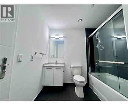 A white bathroom with a toilet, sink, and shower.