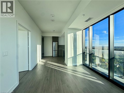 A spacious room with wooden floors and large windows.