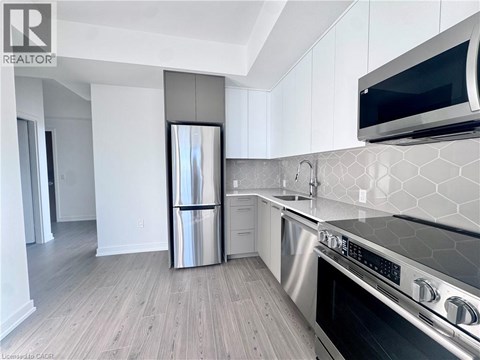 A modern kitchen with a stainless steel refrigerator and oven.