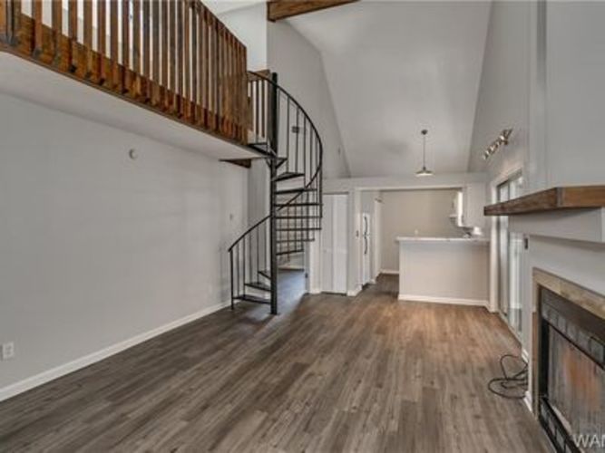 A spacious room with wooden floors and a spiral staircase.