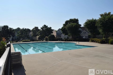 A large outdoor swimming pool surrounded by trees and a residential area.