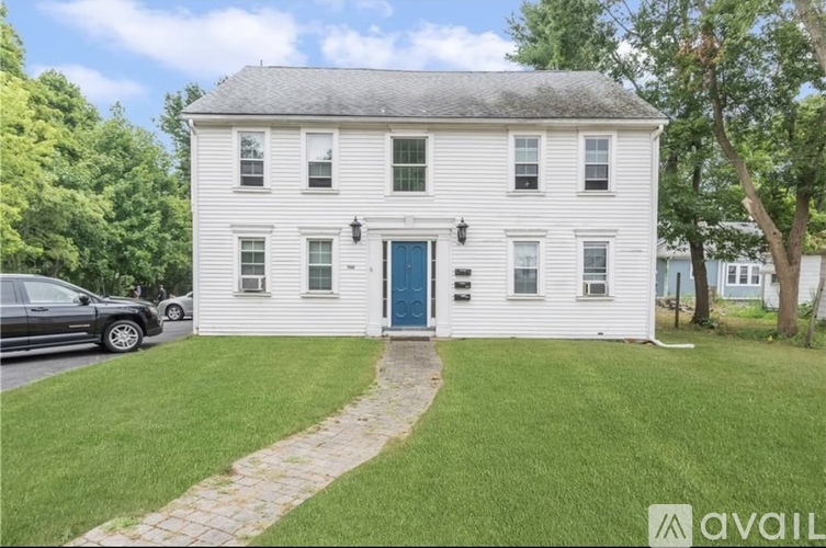 A white house with a blue door and a car parked in front.