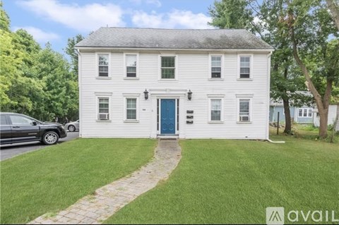 A white house with a blue door and a car parked in front.
