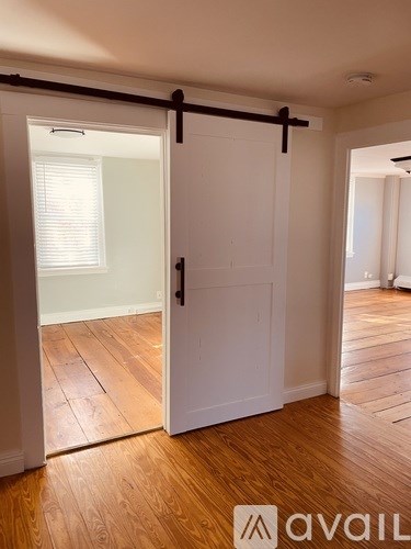 A room with a white door and wooden flooring.