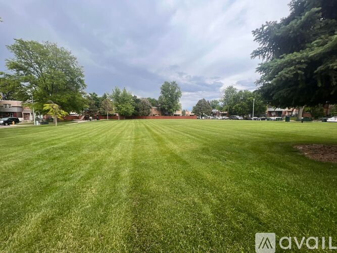 A large, well-maintained grassy field with trees and buildings in the distance.