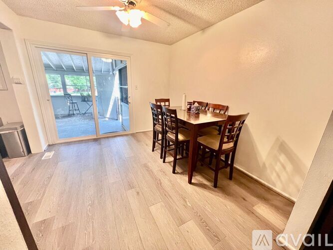 A dining room with a table and chairs and a sliding glass door.