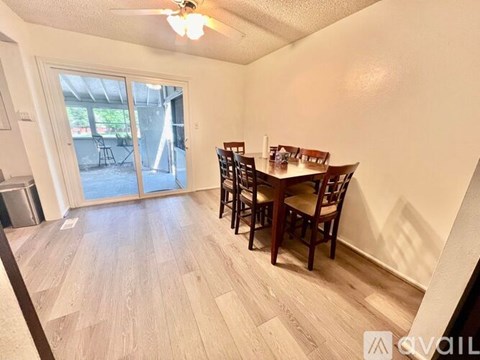 A dining room with a table and chairs and a sliding glass door.