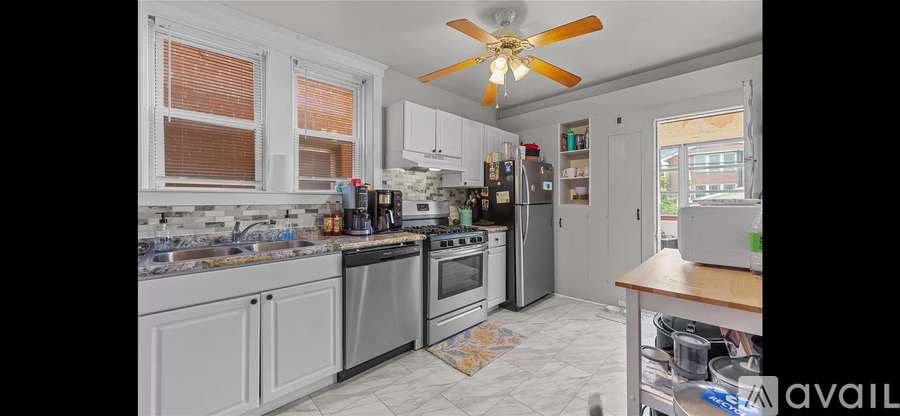 A kitchen with a fan on the ceiling and a refrigerator on the right.