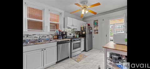 A kitchen with a fan on the ceiling and a refrigerator on the right.