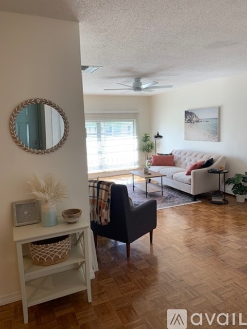 A living room with a white sofa and a round mirror on the wall.