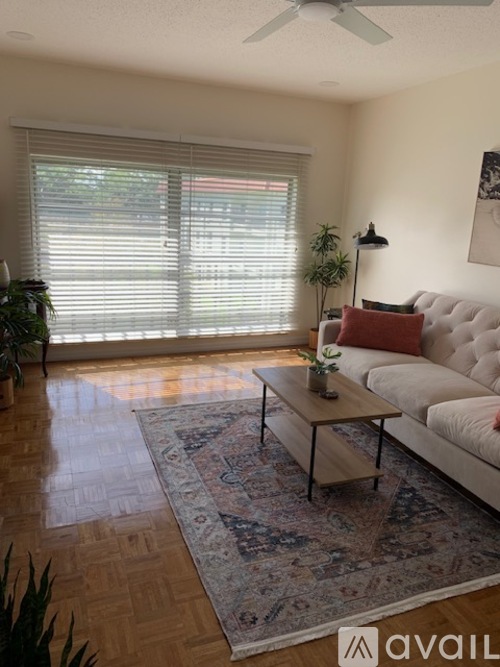 A living room with a white couch, a wooden coffee table, and a rug.