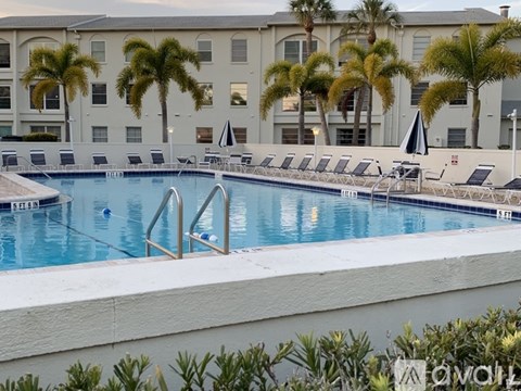 A pool surrounded by palm trees and lounge chairs.