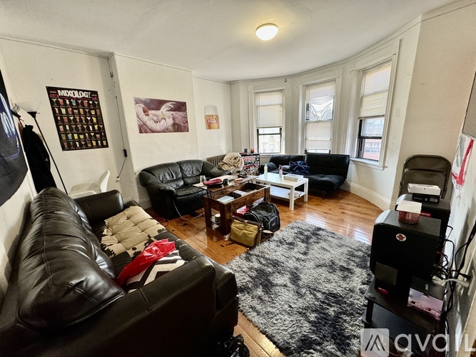 A living room with a black leather couch and a grey rug.