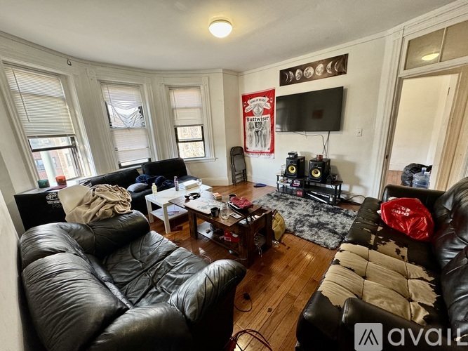 A living room with black leather couches and a flat screen TV mounted on the wall.