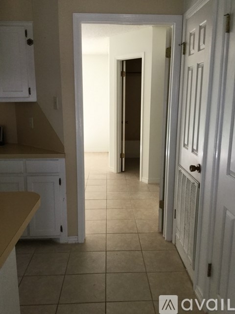 A hallway with a white door and a white wall.
