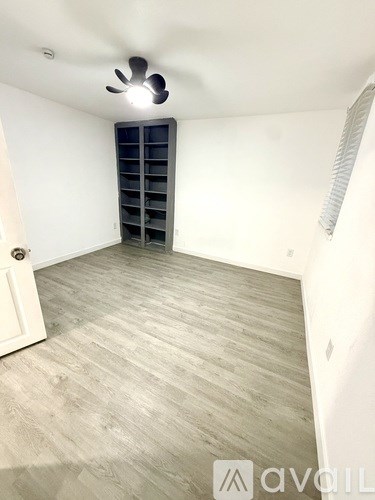 A room with a white door and a fan on the ceiling.