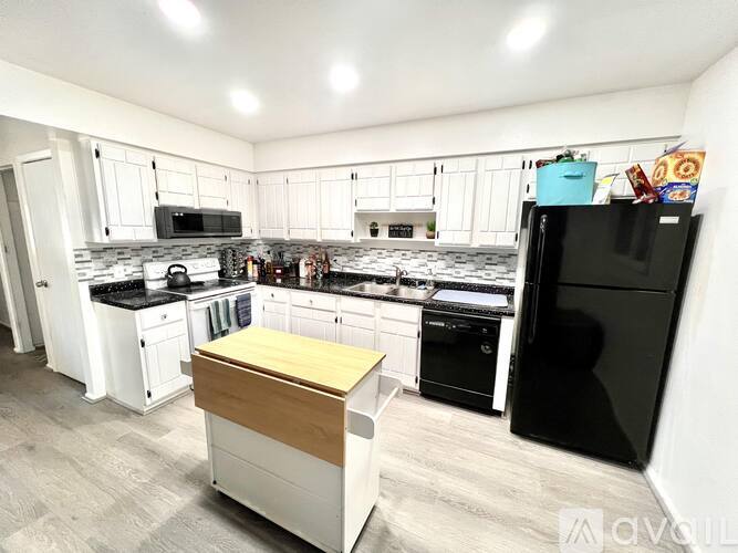 A kitchen with black appliances and white cabinets.
