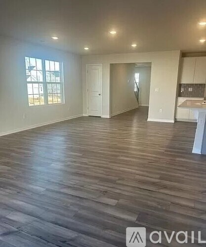 A spacious room with wooden flooring and white walls.