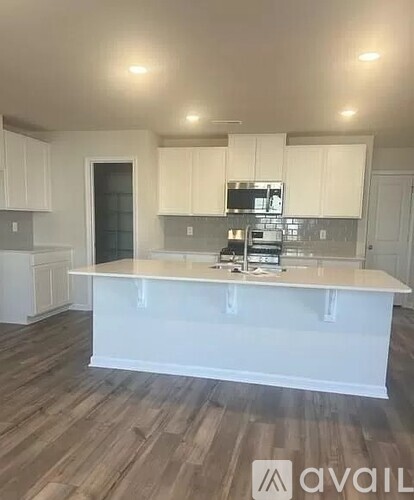 A kitchen with white cabinets and a wooden floor.