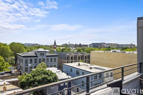 A view from a balcony overlooking a cityscape with buildings and a church spire.