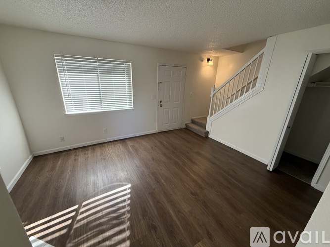 A room with wooden floors and a staircase leading to another room.