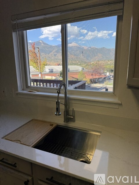 A kitchen sink under a window with a mountain view.