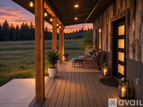 A wooden deck with chairs and a table is lit up at dusk.
