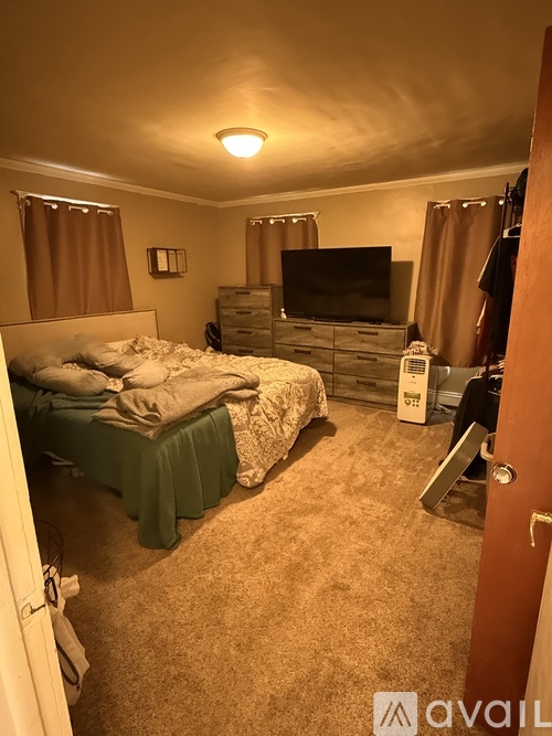 A bedroom with a bed, dresser, and television.