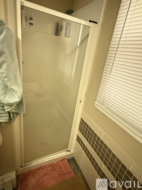 A bathroom with a glass shower door and a towel hanging on the door.