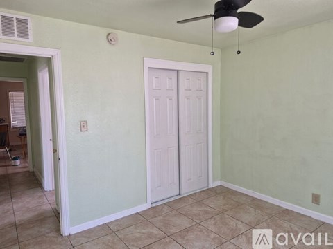 A room with a ceiling fan and two doors.