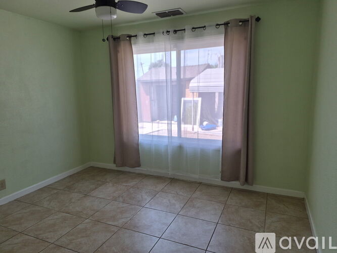 A room with a fan, tiled floor, and a sliding glass door.