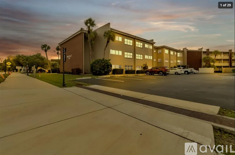 A parking lot in front of a building with a sunset in the background.