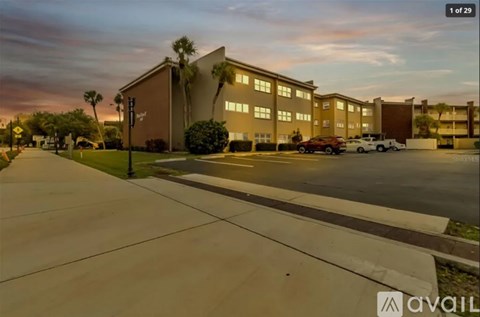 A parking lot in front of a building with a sunset in the background.