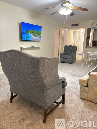 A living room with a grey sofa and a television on the wall.