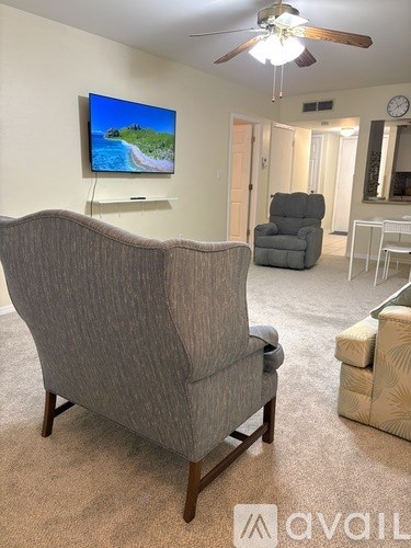 A living room with a grey sofa and a television on the wall.