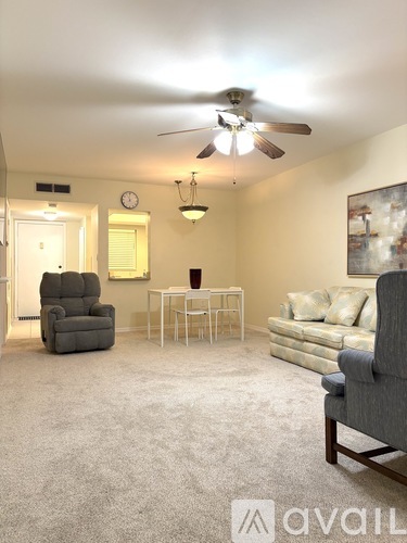 A living room with a grey carpet and furniture.