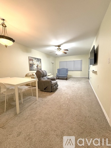 A living room with a white table and chairs, a grey sofa, and a television.