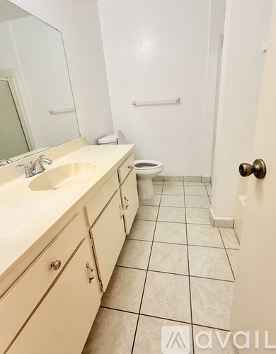 A bathroom with a sink, mirror, toilet and a tiled floor.