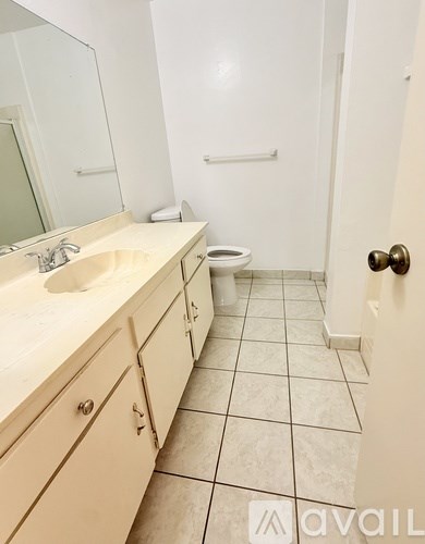 A bathroom with a sink, mirror, toilet and a tiled floor.