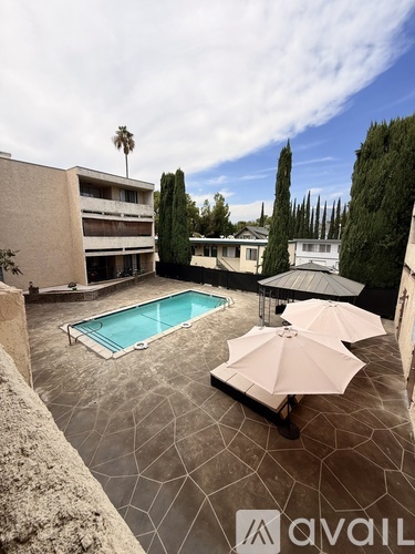 A pool surrounded by a patio and umbrellas.