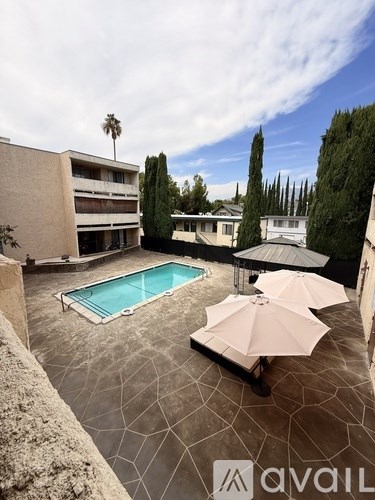 A pool surrounded by a patio and umbrellas.